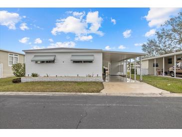 Single-wide mobile home with carport and landscaped yard at 115 White Oak Way, Sarasota, FL 34237
