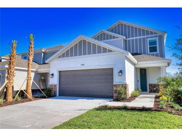 Two-story home with gray siding, brown garage door, and landscaping at 15060 Shady Palms Ln, Nokomis, FL 34275