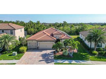 Charming single-story home with a brick driveway, tile roof, and a well-manicured front lawn with palm trees at 20590 Granlago Dr, Venice, FL 34293