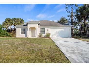 Charming single-story home featuring a two-car garage, well-kept lawn, and inviting front entrance at 3324 Stockton Ave, North Port, FL 34286