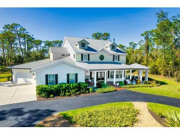 Beautiful two-story home featuring a metal roof, covered porch, and meticulously landscaped front yard at 340 N River Rd, Venice, FL 34293