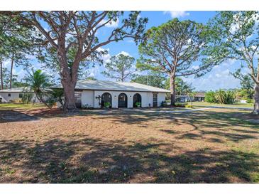 White single story home with arched entry and mature landscaping at 407 Degas Dr, Nokomis, FL 34275