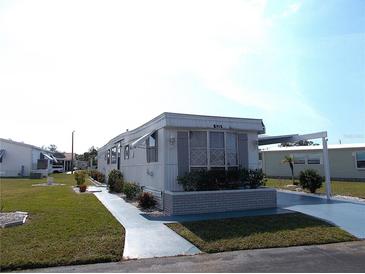 Mobile home with landscaped lawn, driveway, and carport at 426 Boxwood Dr, Venice, FL 34285