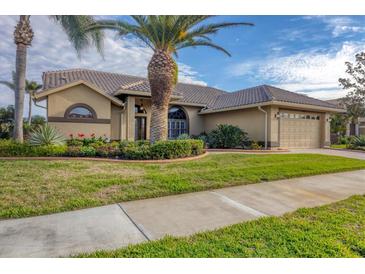 Tan house with tile roof, palm tree, landscaped yard, and driveway at 4621 Gaeta Dr, Venice, FL 34293