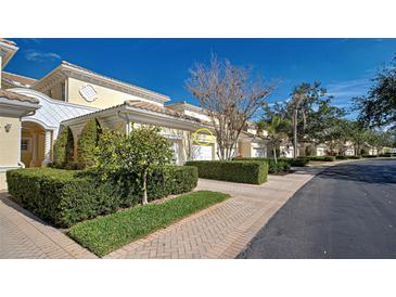 Light yellow building with white garage doors and neatly trimmed hedges at 804 Triano Cir # 804, Venice, FL 34292