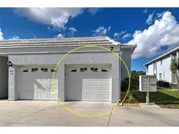 Two-car garage with white doors on a sunny day at 1041 Capri Isles Blvd # 119, Venice, FL 34292