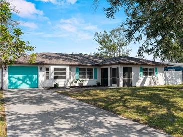 Charming single-story home featuring a bright turquoise garage door, complemented by lush landscaping and a spacious driveway at 1212 Mango Ave, Venice, FL 34285