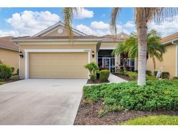 Tan house with two-car garage, landscaping, and a bird statue at 27231 Ipswich Dr, Englewood, FL 34223