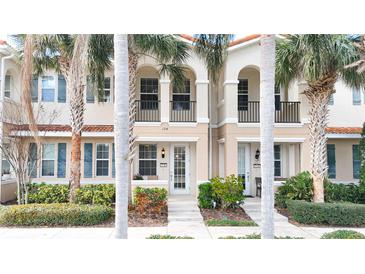 Charming townhome exterior with a private balcony, mature palm trees, and beautifully landscaped front yard at 3730 82Nd Avenue E Cir # 104, Sarasota, FL 34243