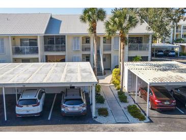 Condo building exterior with white shutters, palm trees, covered parking and staircase entry at 435 Cerromar Ln # 328, Venice, FL 34293