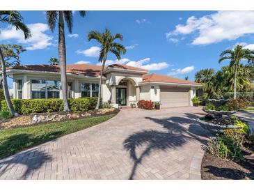 Charming home featuring lush landscaping, brick driveway, a three-car garage and a tile roof at 612 Cadiz Rd, Venice, FL 34285