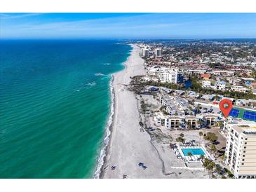 Stunning aerial view of beachside condos with pool and the Gulf's turquoise waters and sandy beach at 700 Golden Beach Blvd # 221, Venice, FL 34285