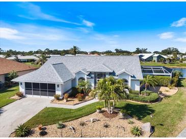 An eye-level view of a home with a white exterior, lush landscaping, and an adjacent screened-in pool and waterfront area at 734 Sugarwood Way, Venice, FL 34292