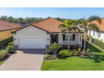 Charming single Gathering home with a well manicured lawn, paver driveway, and a tile roof at 10181 Colubrina Dr, Venice, FL 34293