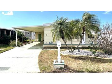 Charming single Gathering home featuring a welcoming front yard, palm trees, and covered parking at 105 Lakeview Dr, North Port, FL 34287