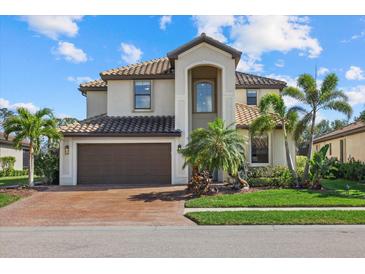 Beautiful two-story home featuring a tile roof, manicured lawn, and lush tropical landscaping at 12279 Canavese Ln, Venice, FL 34293