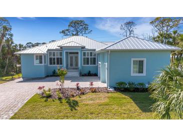 Charming single-story home with light blue exterior, manicured lawn, and a light-colored metal roof at 1596 Landfall Dr, Nokomis, FL 34275