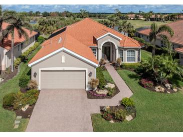 Charming home with a red tile roof, two-car garage, lush landscaping, and inviting curb appeal at 190 Montelluna Dr # North, North Venice, FL 34275