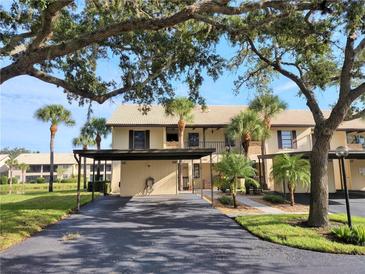 Inviting condo exterior with mature trees, covered parking, and well-maintained landscaping at 345 Three Lakes Ln # L, Venice, FL 34285