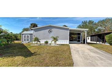 Charming gray home featuring well-maintained landscaping and a covered carport in a lovely community at 6665 Keystone Ct, North Port, FL 34287