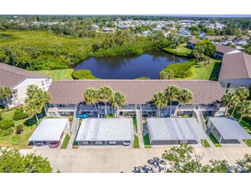 An aerial view of this condo features assigned covered parking and a peaceful pond surrounded by lush landscaping at 811 Waterside Dr # 102, Venice, FL 34285