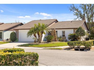 Charming home featuring a well-manicured lawn, palm trees, and a stone accent wall for added curb appeal at 537 Foxwood Blvd, Englewood, FL 34223