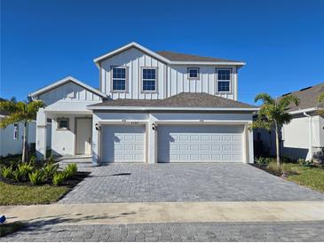 Two-story house with white exterior, two-car garage, and gray paver driveway at 9589 Vibrant Lane, Venice, FL 34292