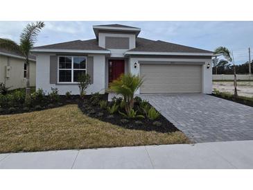 One-story home with gray siding, red door, and paver driveway at 9577 Vibrant Lane, Venice, FL 34292