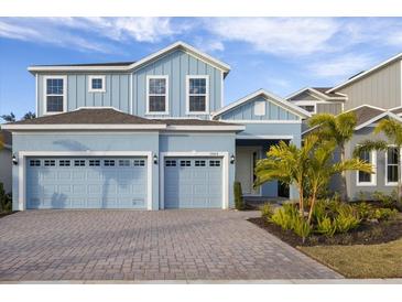 Two-story light blue house with a three-car garage and a landscaped front yard at 1005 Signet, Apollo Beach, FL 33572