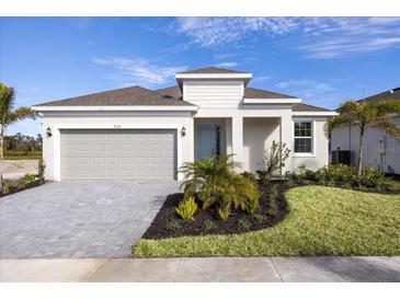 One-story home with gray garage door, landscaping, and paver driveway at 9572 Vibrant Lane, Venice, FL 34292