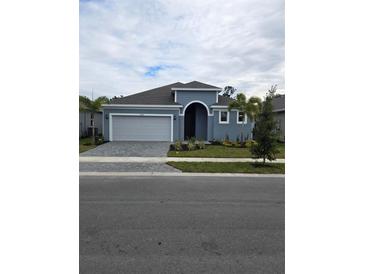 Newly constructed home with gray exterior, two-car garage, and landscaped yard at 9584 Vibrant Lane, Venice, FL 34292