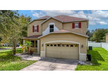 Two-story house with tan exterior, red accents, and a two-car garage at 10617 Bamboo Rod Cir, Riverview, FL 33569