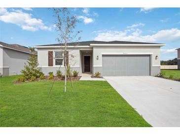 Single-story home with gray garage door and well-manicured lawn at 37513 Williamette Way, Zephyrhills, FL 33540