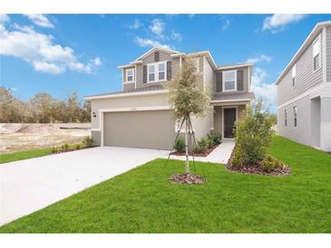 Two-story house with gray siding, two-car garage, and a landscaped lawn at 37736 Yukon Dr, Zephyrhills, FL 33540