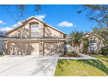 Two-story house with three-car garage, and landscaped lawn at 8612 Swann Ridge Ct, Tampa, FL 33647