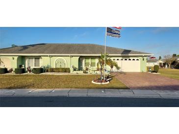 Single-story home with green exterior, landscaped yard, and paved driveway at 906 Bluewater Dr, Sun City Center, FL 33573