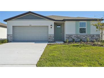 New single-story home with gray siding, stone accents and a two-car garage at 7806 Gilchrist Springs Dr, Parrish, FL 34219