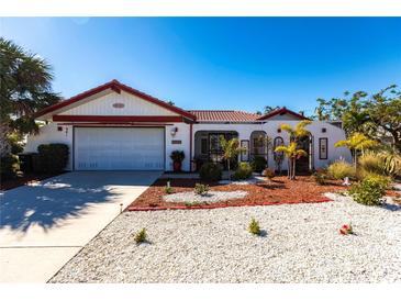 White single-story home with red accents, a two-car garage, and a landscaped yard at 901 Don Juan Ct, Punta Gorda, FL 33950