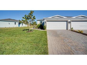 Two-car garage, paver driveway, and grassy yard at 16093 Ivy Ridge Ct, Port Charlotte, FL 33953