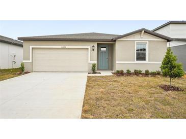 Tan house with a two-car garage and teal front door at 31650 Malbec Dr, Brooksville, FL 34602