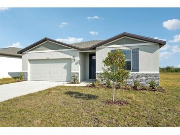 One-story house with gray siding, stone accents, and a two-car garage at 31703 Wild Grape Ln, Brooksville, FL 34602