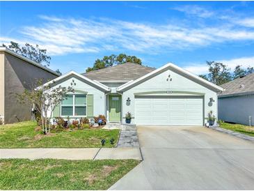 Single-story home with green accents and a two-car garage at 7729 Rosewood Garden Loop, Tampa, FL 33637