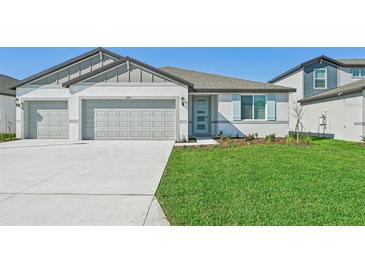 Newly constructed home with a two-car garage and well-manicured lawn at 13851 Richland Gulf Cir, Parrish, FL 34219