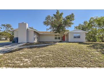 Ranch-style home with a red door, well-maintained lawn, and mature trees at 6256 Kimball Ct, Spring Hill, FL 34606
