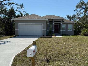 Charming single-story home with a well-maintained lawn and a two-car garage at 135 Sunset Rd, Rotonda West, FL 33947