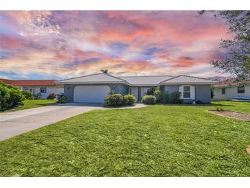 Single-story house with a gray exterior, attached garage, and well-maintained lawn at 72 Windsor Dr, Englewood, FL 34223