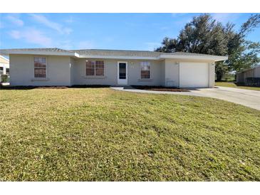 Newly renovated single-story home with a spacious lawn and attached garage at 3944 Nekoosa St, North Port, FL 34287