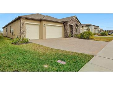 Two-car garage, stone accents, and landscaped lawn at 8796 Little Bluestem Dr, Land O Lakes, FL 34637