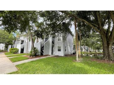 Exterior view of condo building with lush landscaping and pond at 7120 Waterside Dr # 34, Tampa, FL 33617