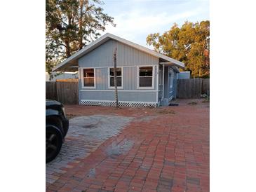 Charming bungalow with gray siding, brick driveway, and mature trees at 718 New York St, Clearwater, FL 33756